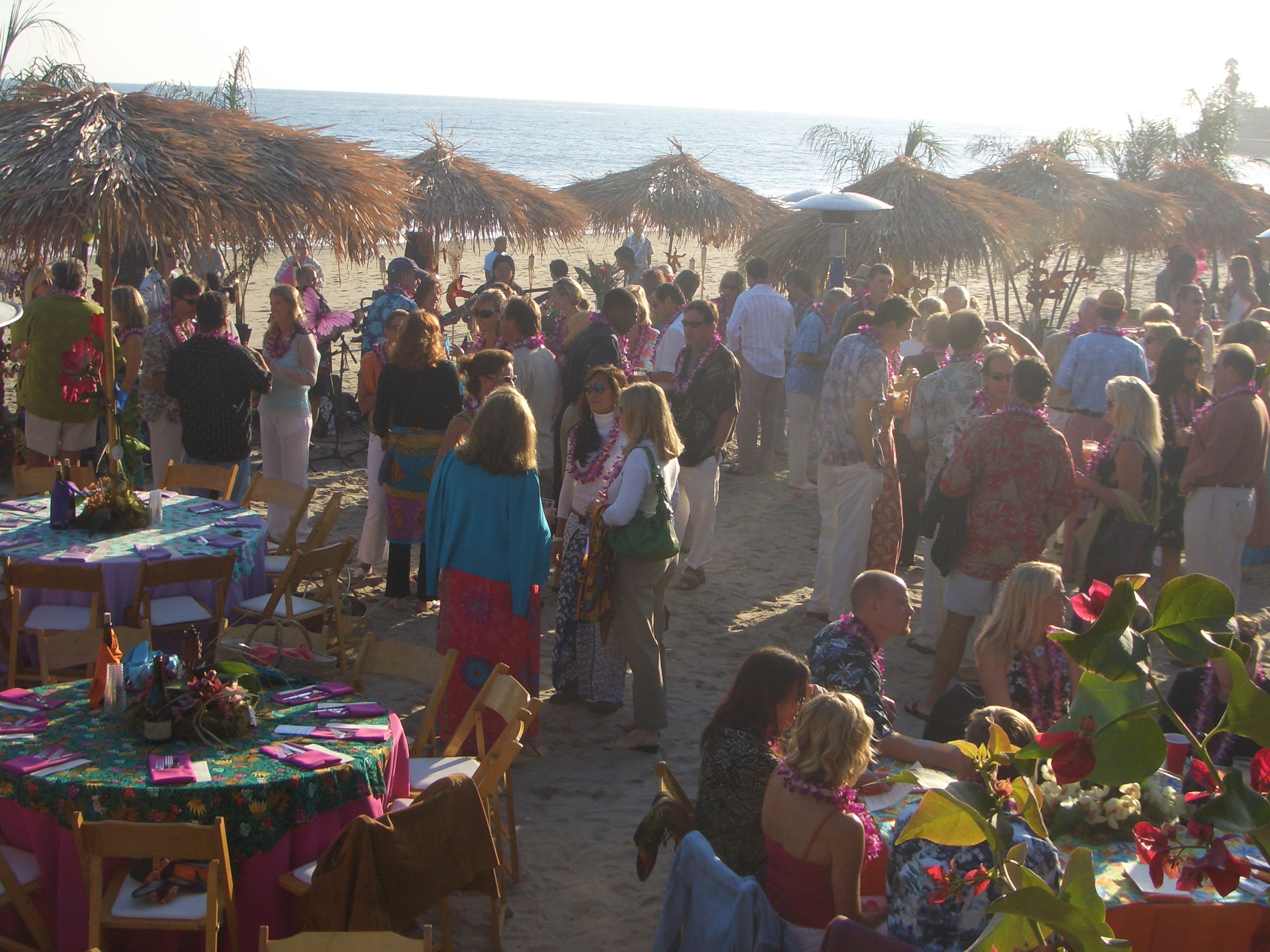 Wide-angle view of a fully decorated outdoor luau venue setup by Manea Florida with tropical staging and lighting